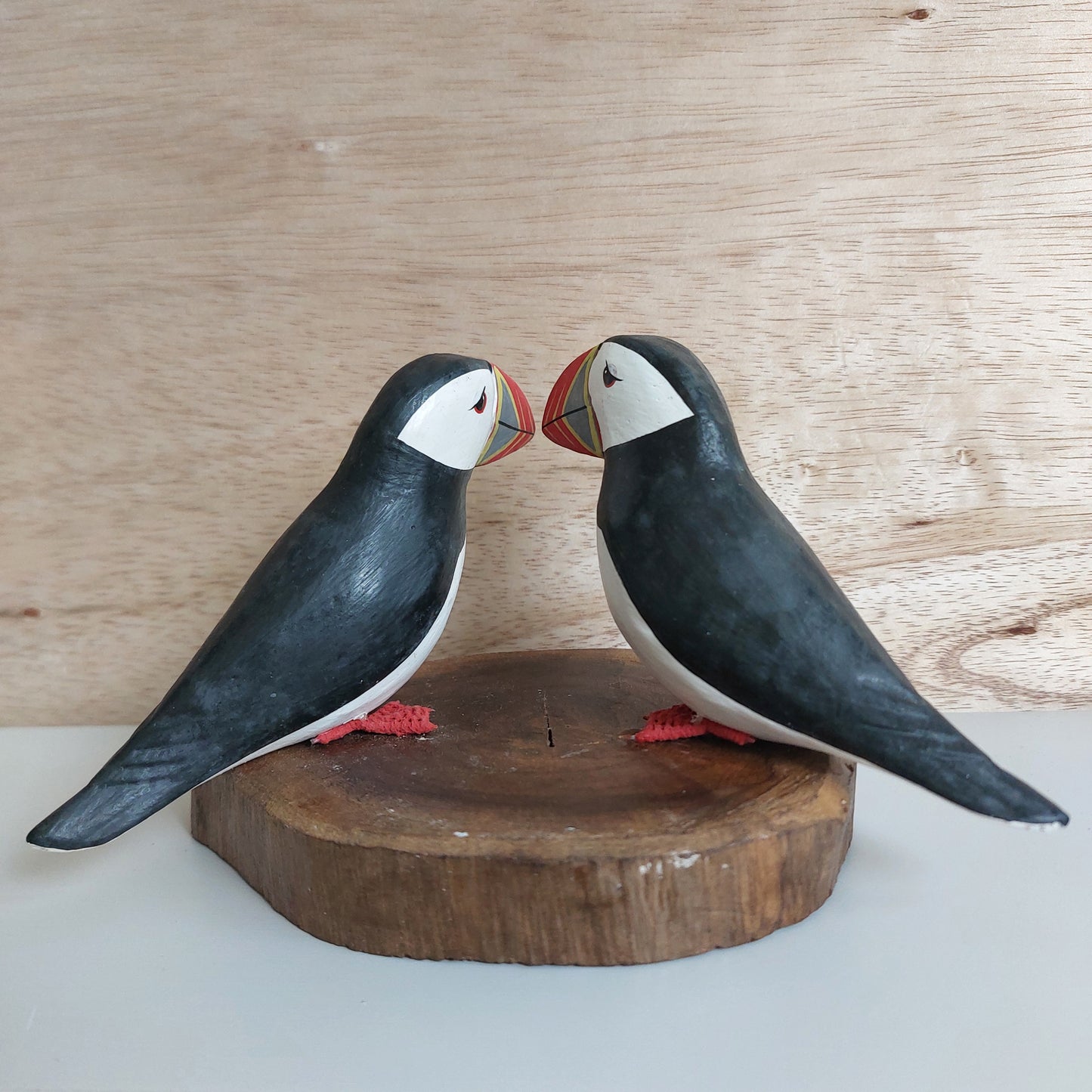 Wooden puffin figurines on a wooden base against a light background