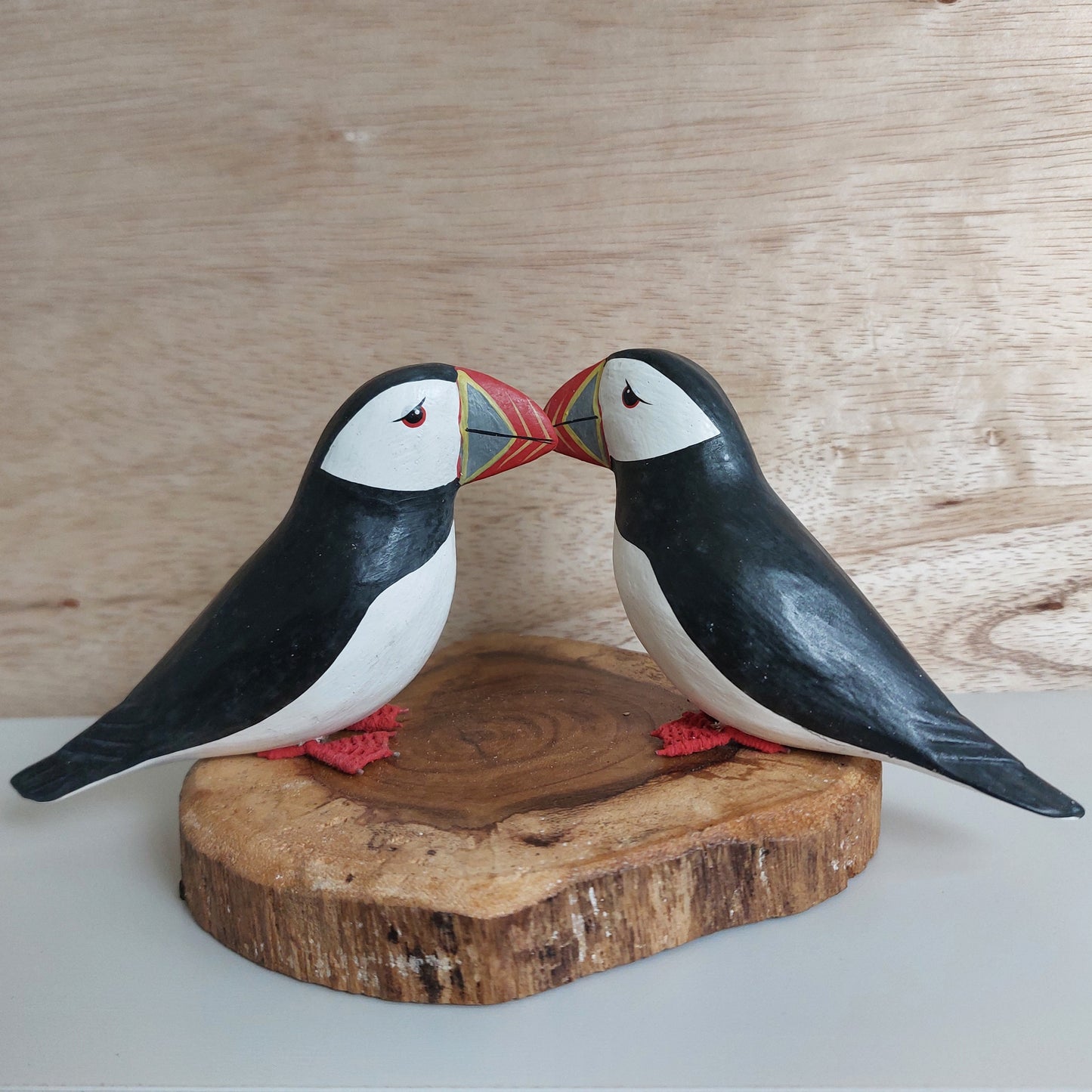 Wooden puffin figurines on a wooden base against a wooden background