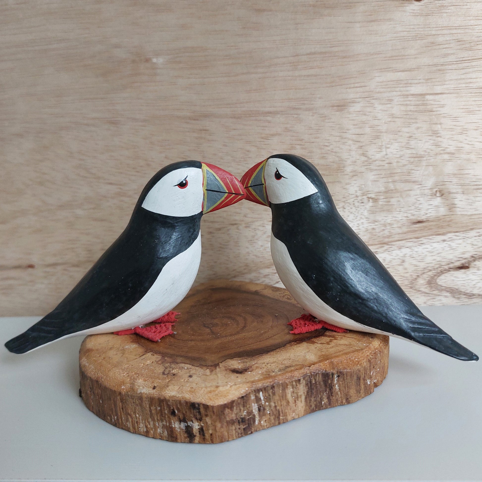 Wooden puffin figurines on a wooden base against a wooden background