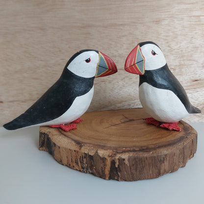 Two hand made and painted puffins mounted on a split wood base against a pale background