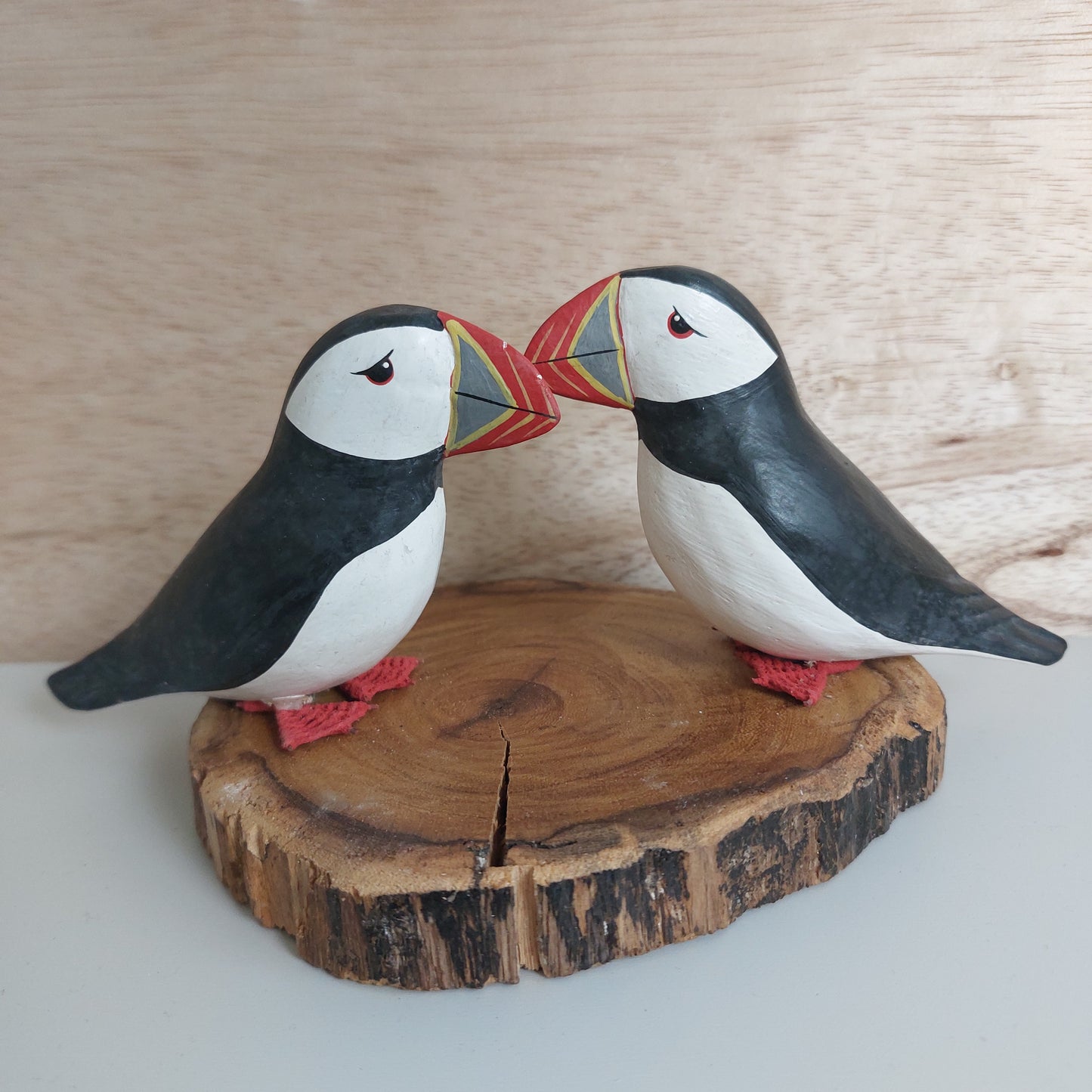 Two hand carved and painted decorative puffins on a wooden surface