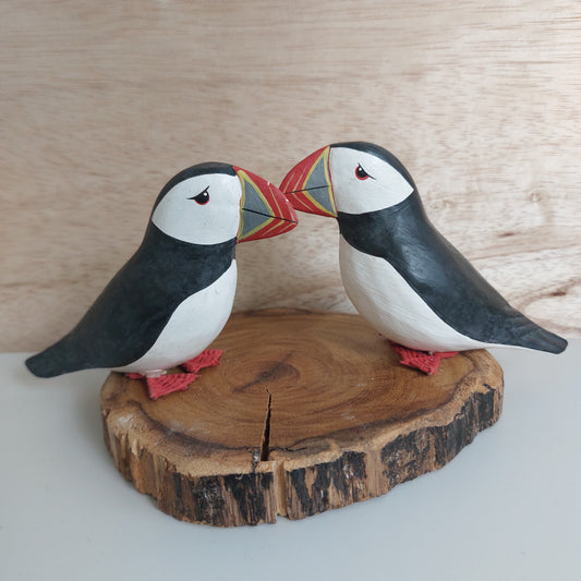 Two hand carved and painted decorative puffins on a wooden surface