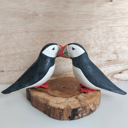 Two wooden puffin figures on a wooden base made in Bali against a wooden background
