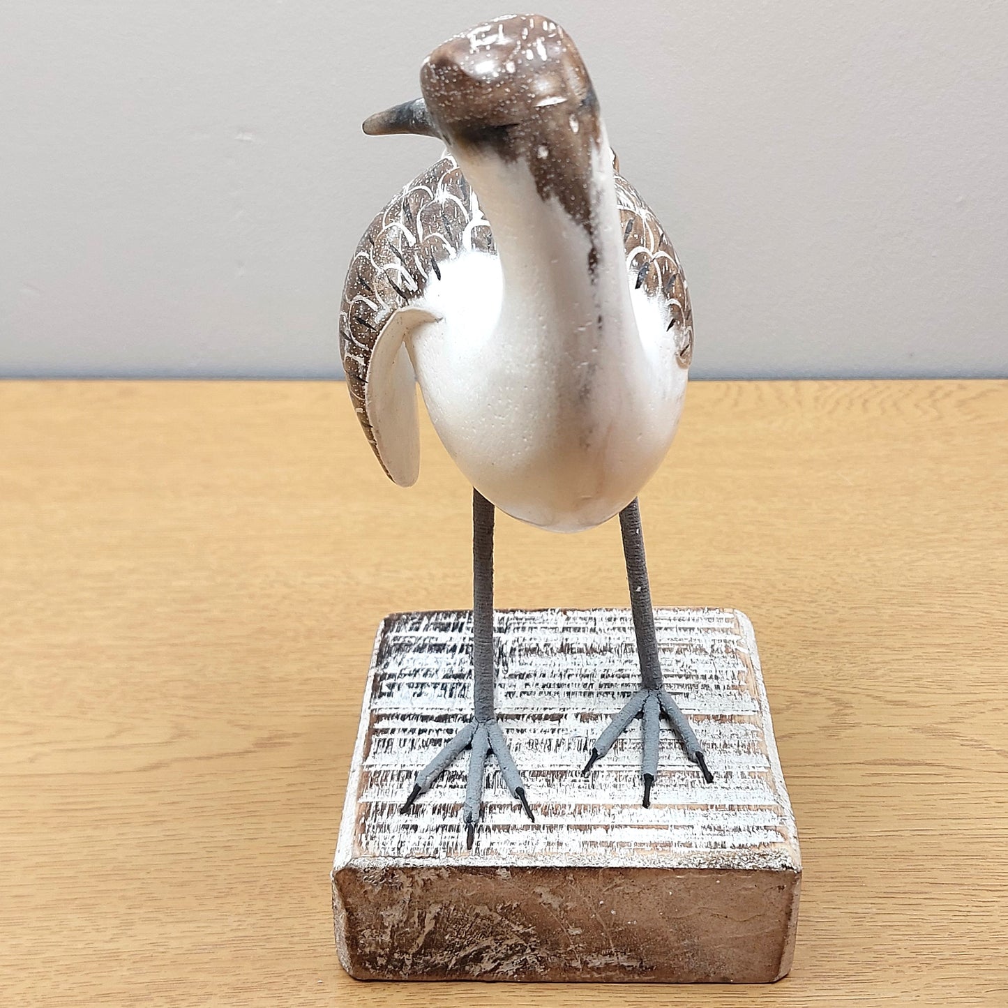 A wooden handmade, painted and carved Godwit bird ornament from Bali, mounted on a whitewashed wooden block.