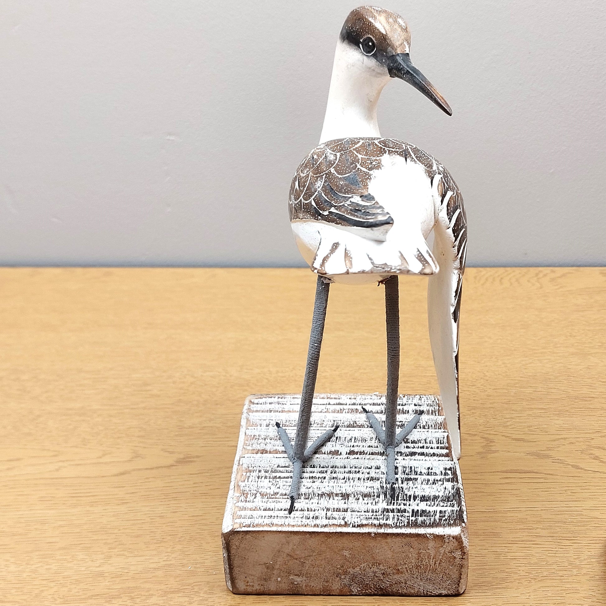 A hand made and painted wooden carving of a Godwit bird mounted on a wooden block.