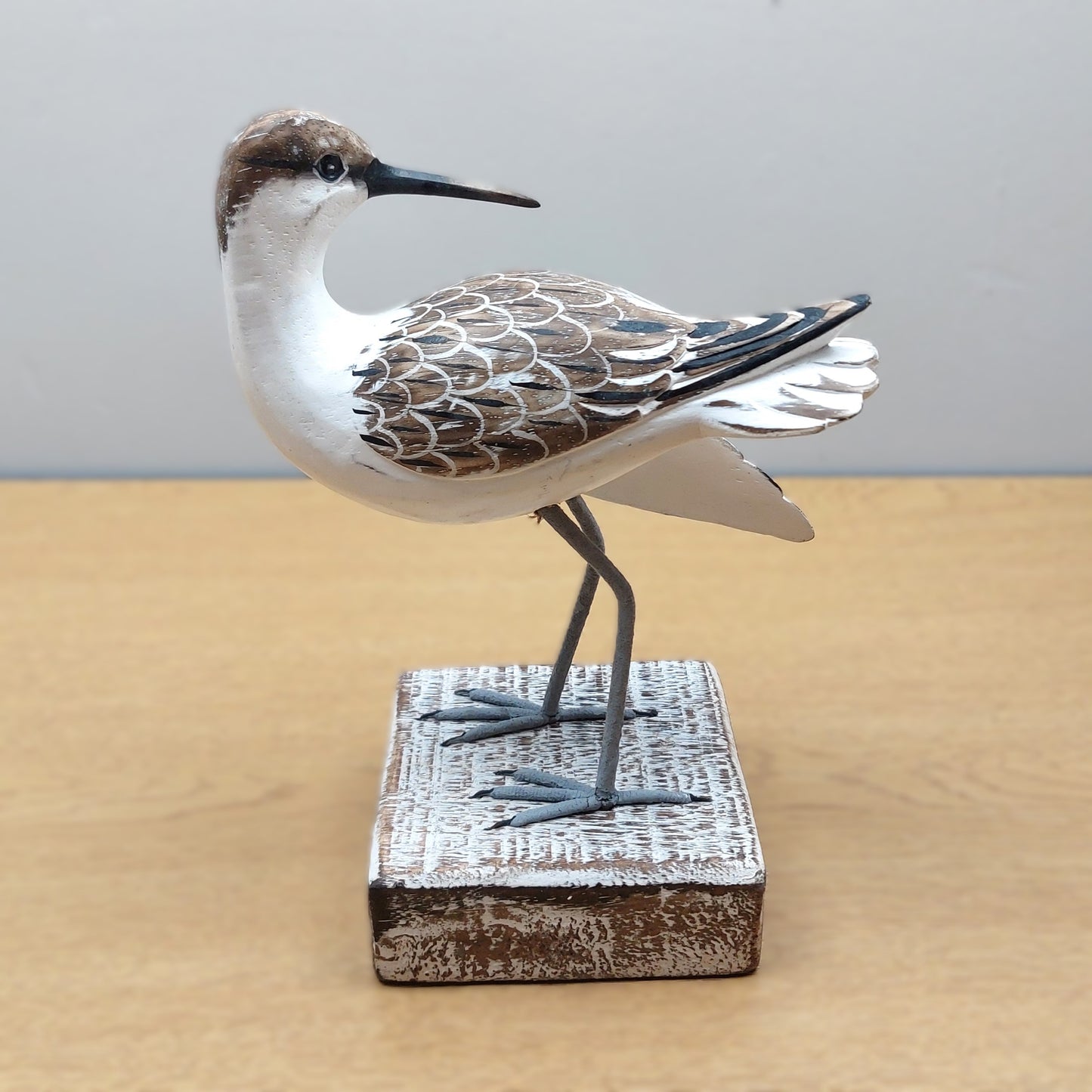 Decorative Hand carved and painted wooden Godwit bird figurine on a wooden base against a plain background