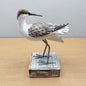 Decorative Hand carved and painted wooden Godwit bird figurine on a wooden base against a plain background