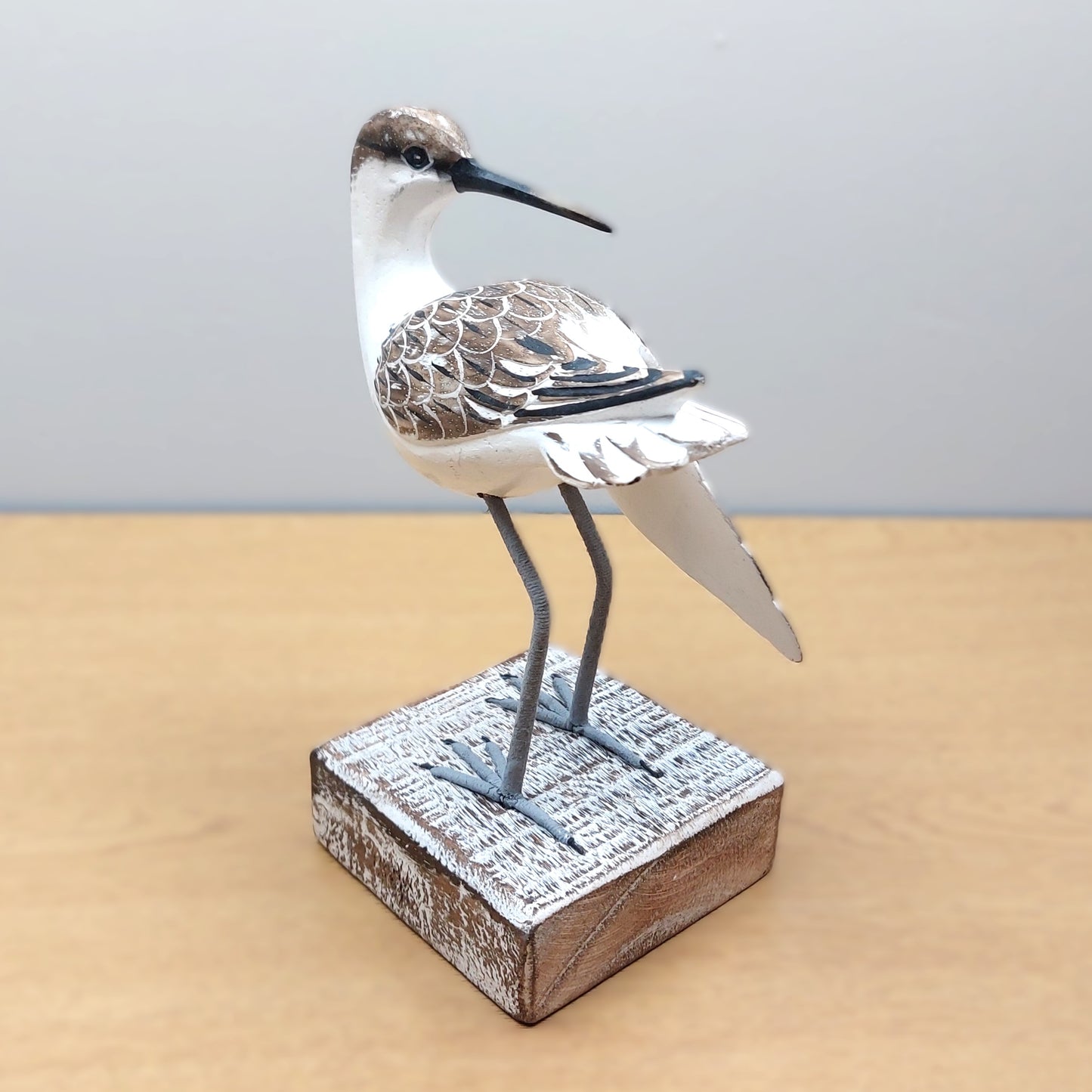 Decorative hand carved and painted Godwit bird sculpture on a wooden base with a plain background