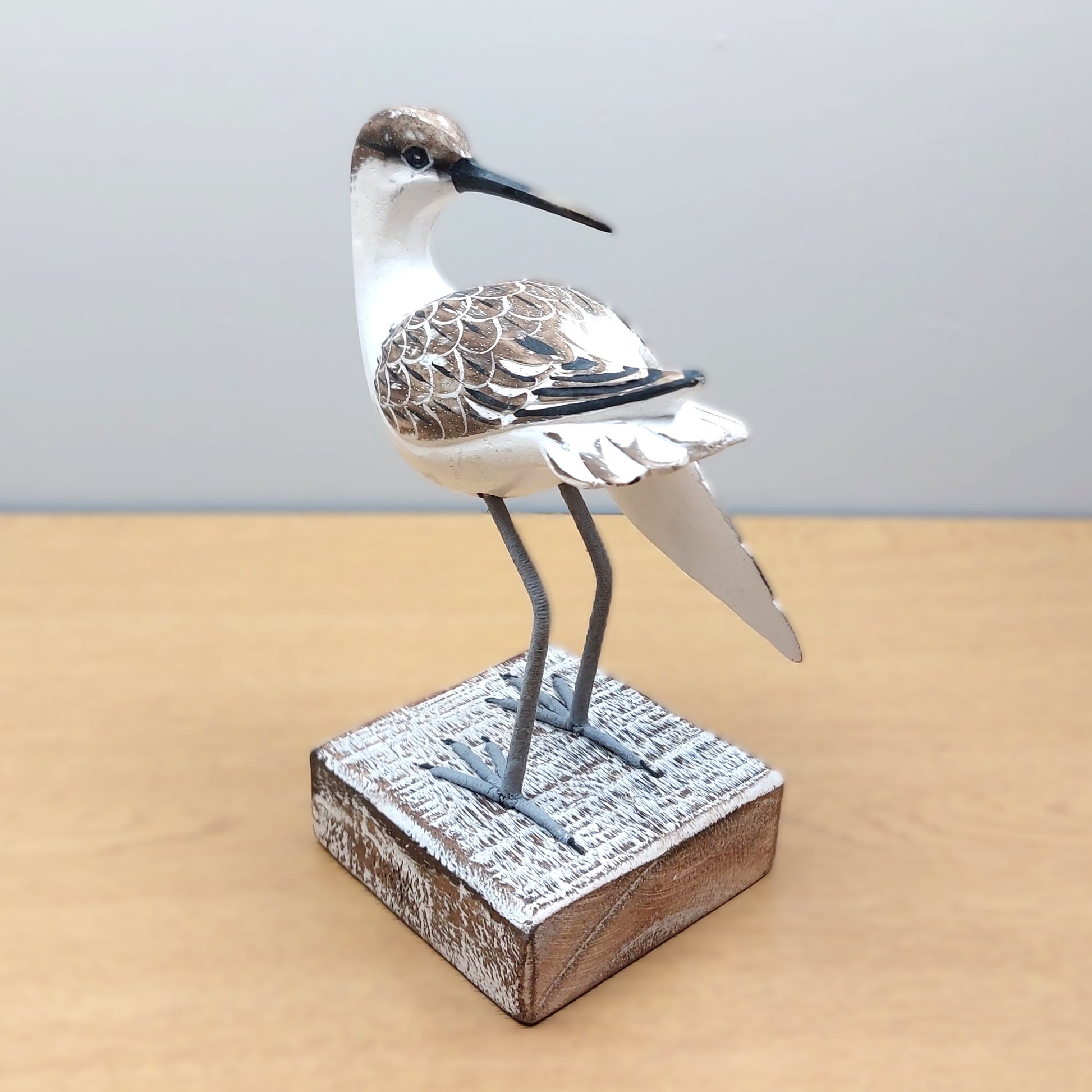Decorative hand carved and painted Godwit bird sculpture on a wooden base with a plain background