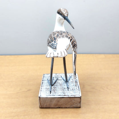 Decorative ornate hand made and painted Godwit bird figurine on a wooden base against a plain background