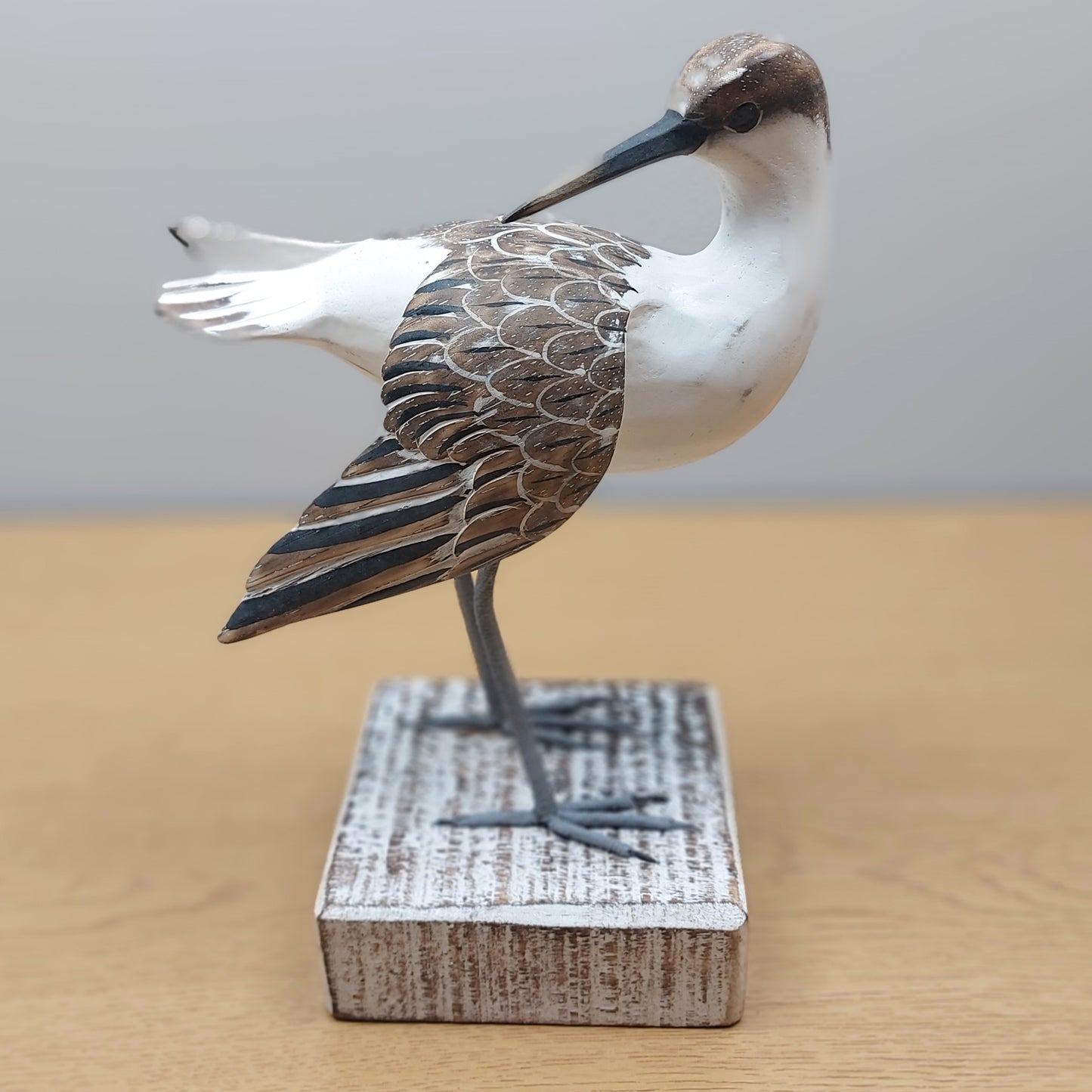 Hand carved and painted Godwit Bird figurine on a wooden base against a plain background