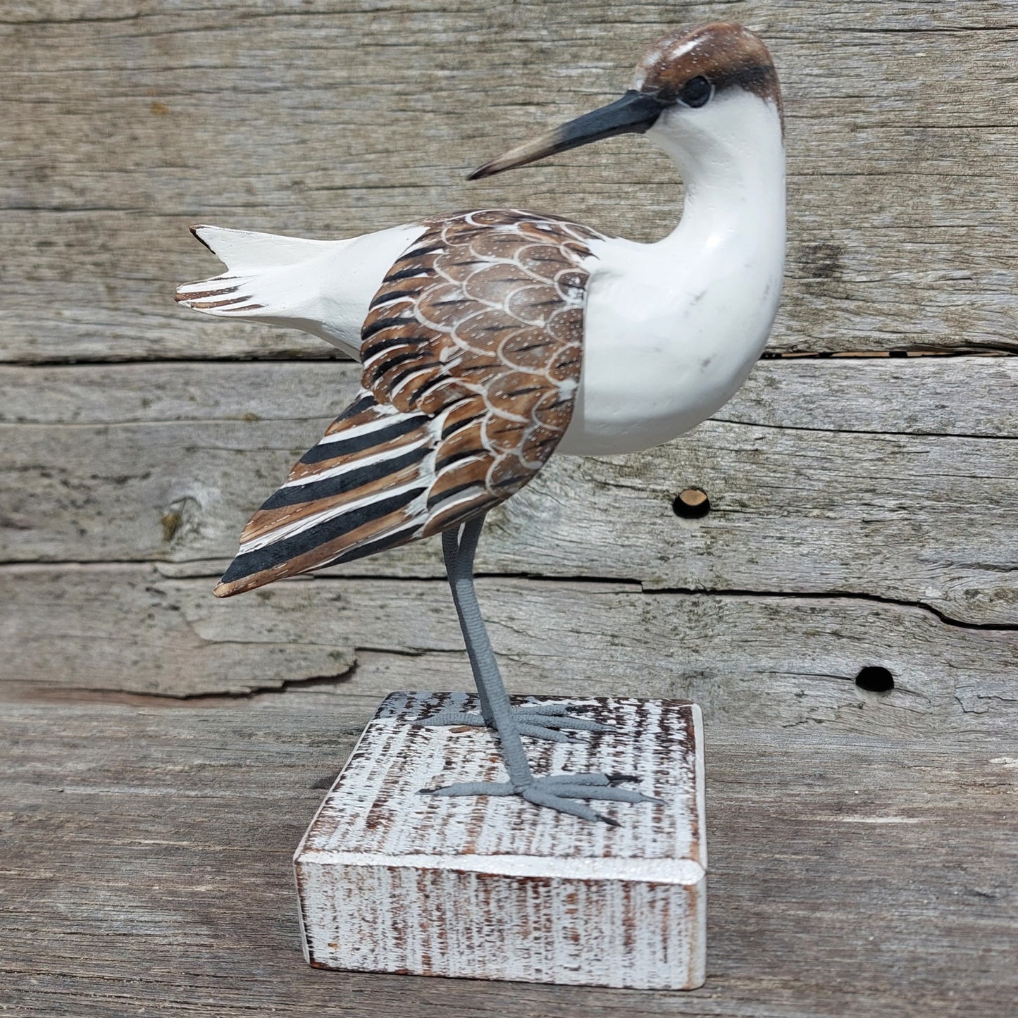 Decorative Godwit wooden bird figure on a wooden block against a wooden background