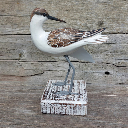 Decorative handmade and painted Godwit bird sculpture on a wooden block against a rustic wooden background