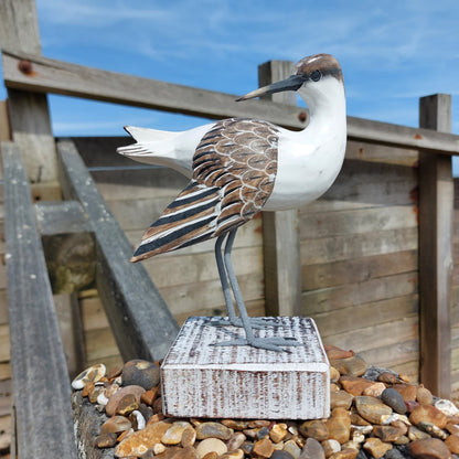 Decorative wooden White and Brown bird sculpture on a wooden structure with a blue sky background