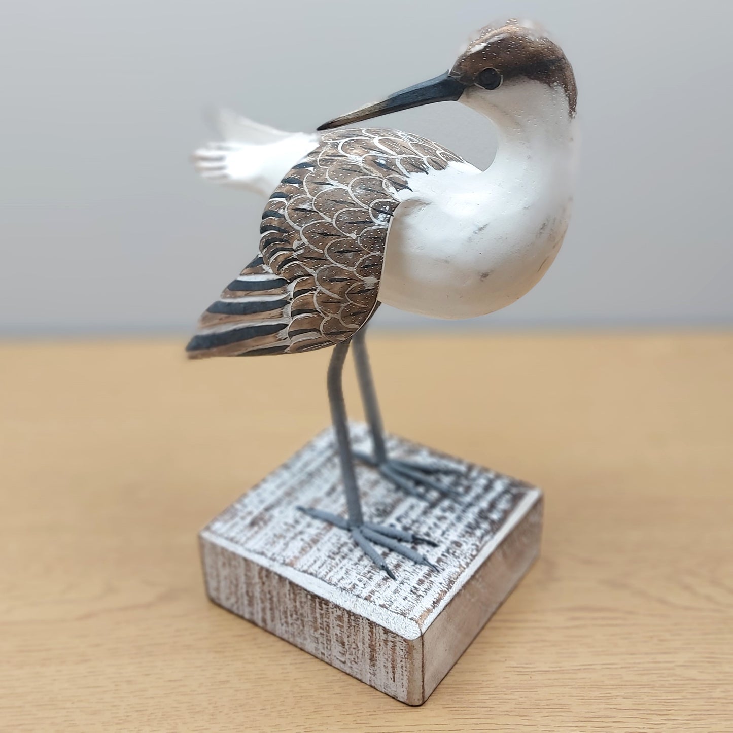 Decorative painted Brown and White Godwit bird figurine on a wooden base with a plain background