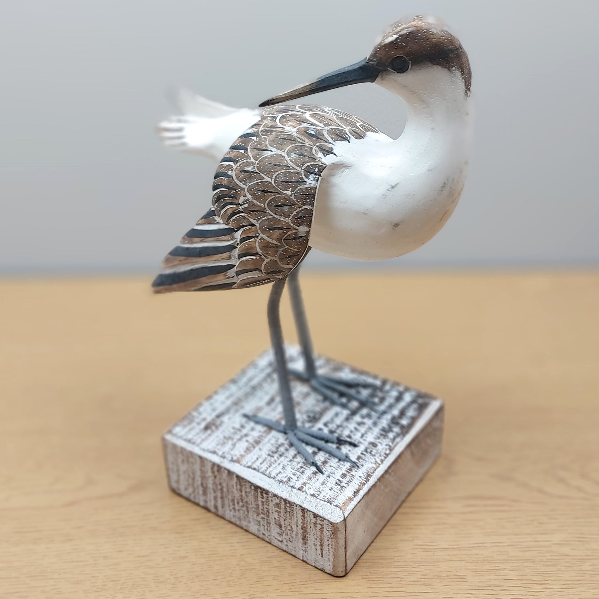 Decorative painted Brown and White Godwit bird figurine on a wooden base with a plain background