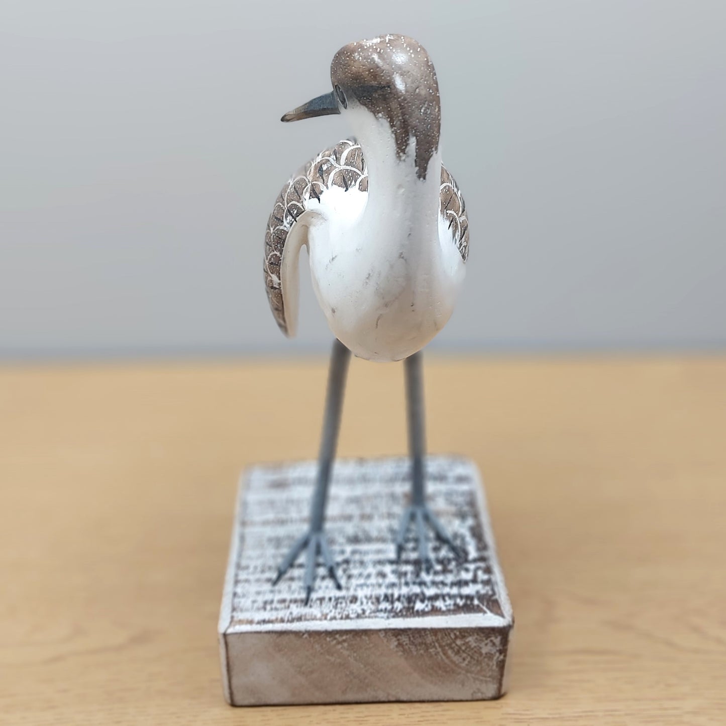 Decorative handmade and painted Godwit bird figurine on a wooden surface with a neutral background