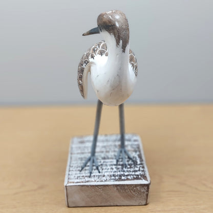 Decorative handmade and painted Godwit bird figurine on a wooden surface with a neutral background