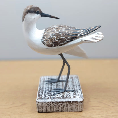 Decorative Godwit bird sculpture on a wooden base with a plain background