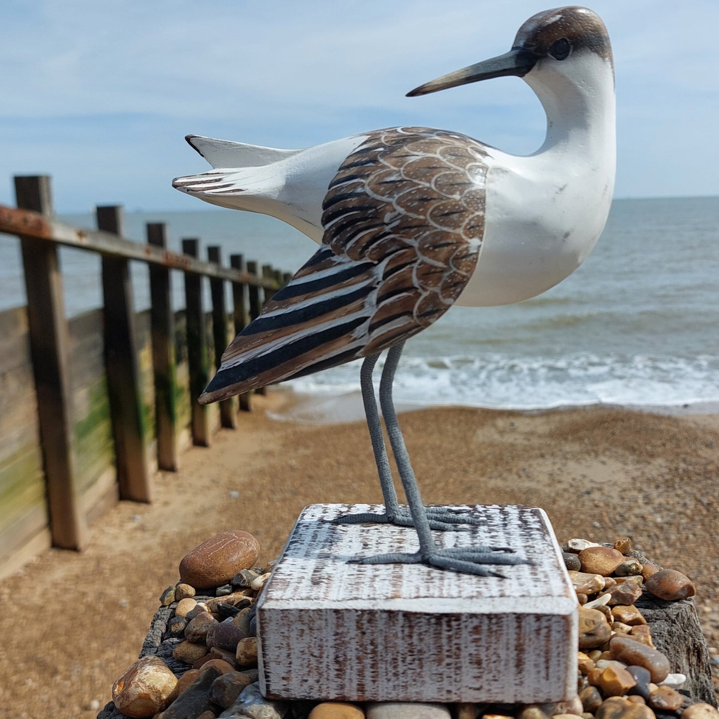Decorative Godwit bird sculpture on a beach with ocean in the background