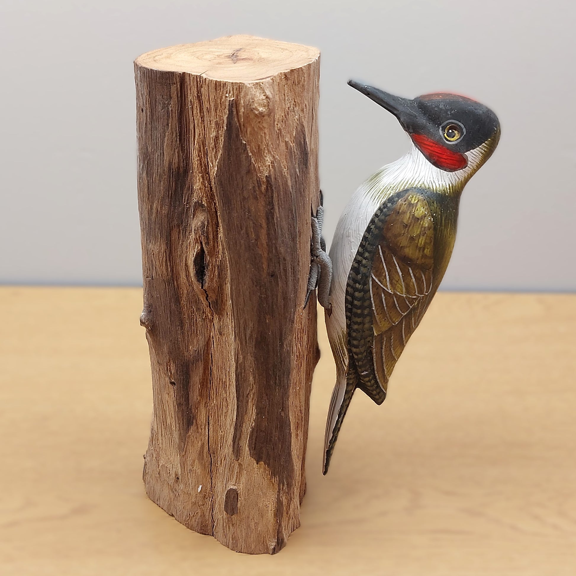 A higher detailed Green Woodpecker figurine with a wooden log against a pale background.