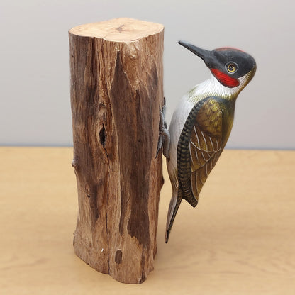A higher detailed Green Woodpecker figurine with a wooden log against a pale background.