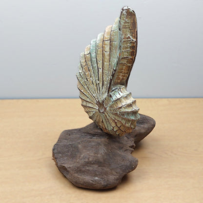 Decorative wood shell sculpture on a wooden base against a plain background