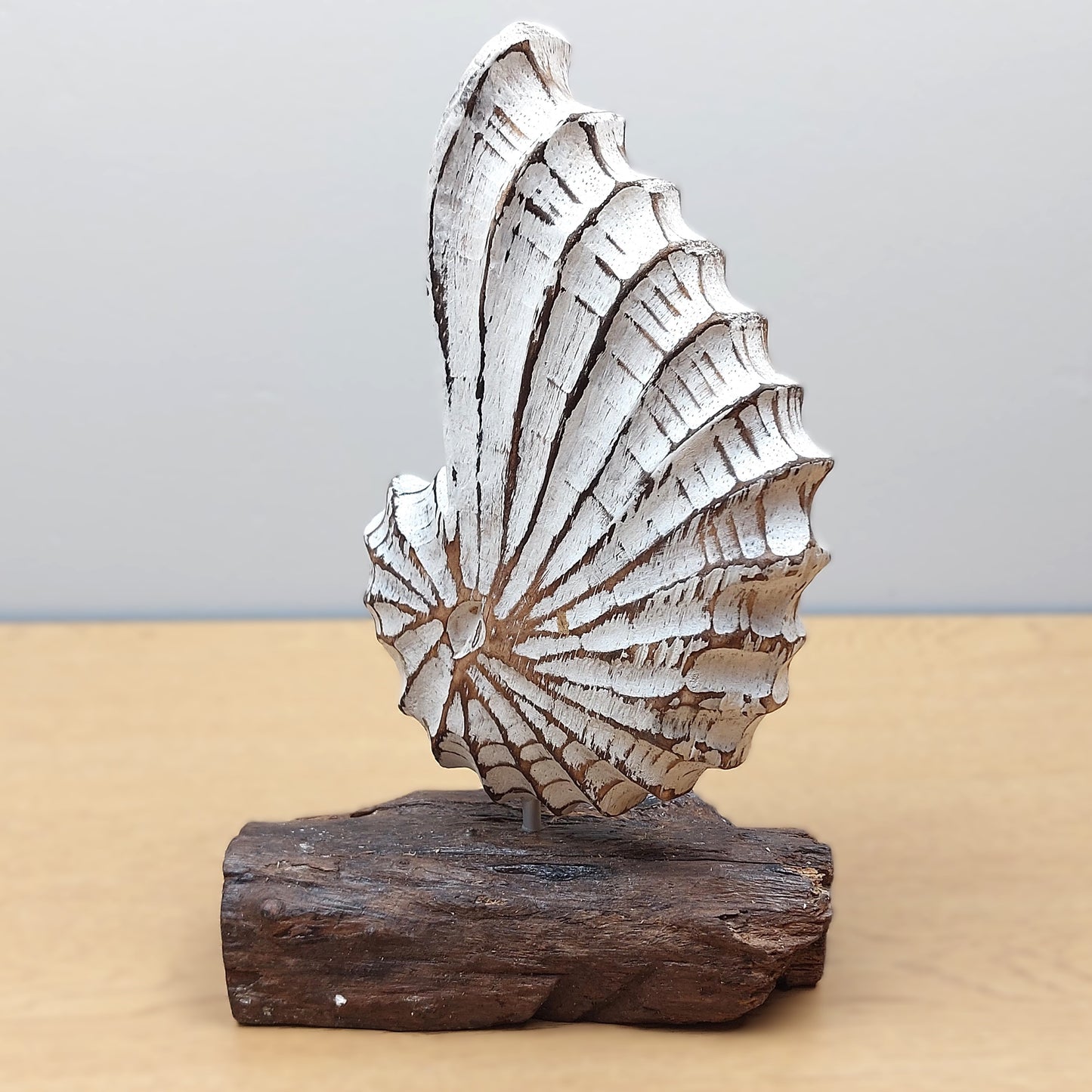 Decorative hand carved and painted shell sculpture on a wooden base from Bali against a neutral background