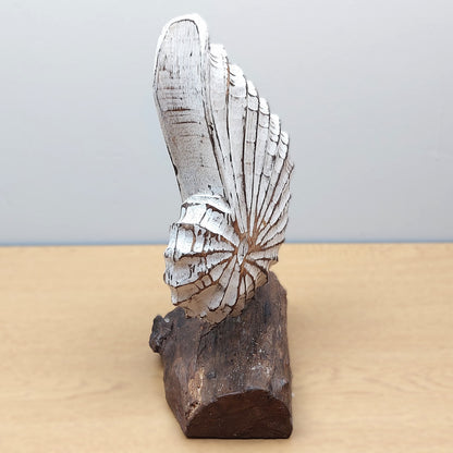 Decorative wooden handmade sculpture of a White shell on a wooden base against a plain background