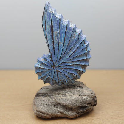Decorative hand carved and painted blue shell sculpture on a wooden base against a plain background
