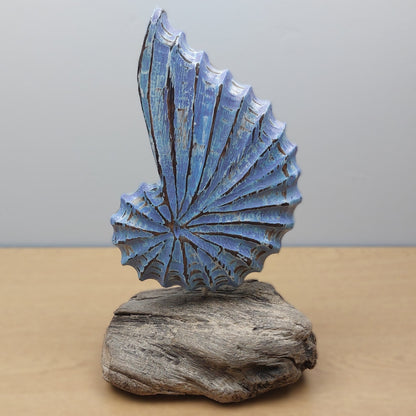 Blue wooden hand crafted in Bali sculpture on a wooden driftwood base against a gray background