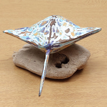 Decorative ornament made in Bali which consists of a Manta Ray mounted on a soft driftwood block of wood on a wooden surface.
