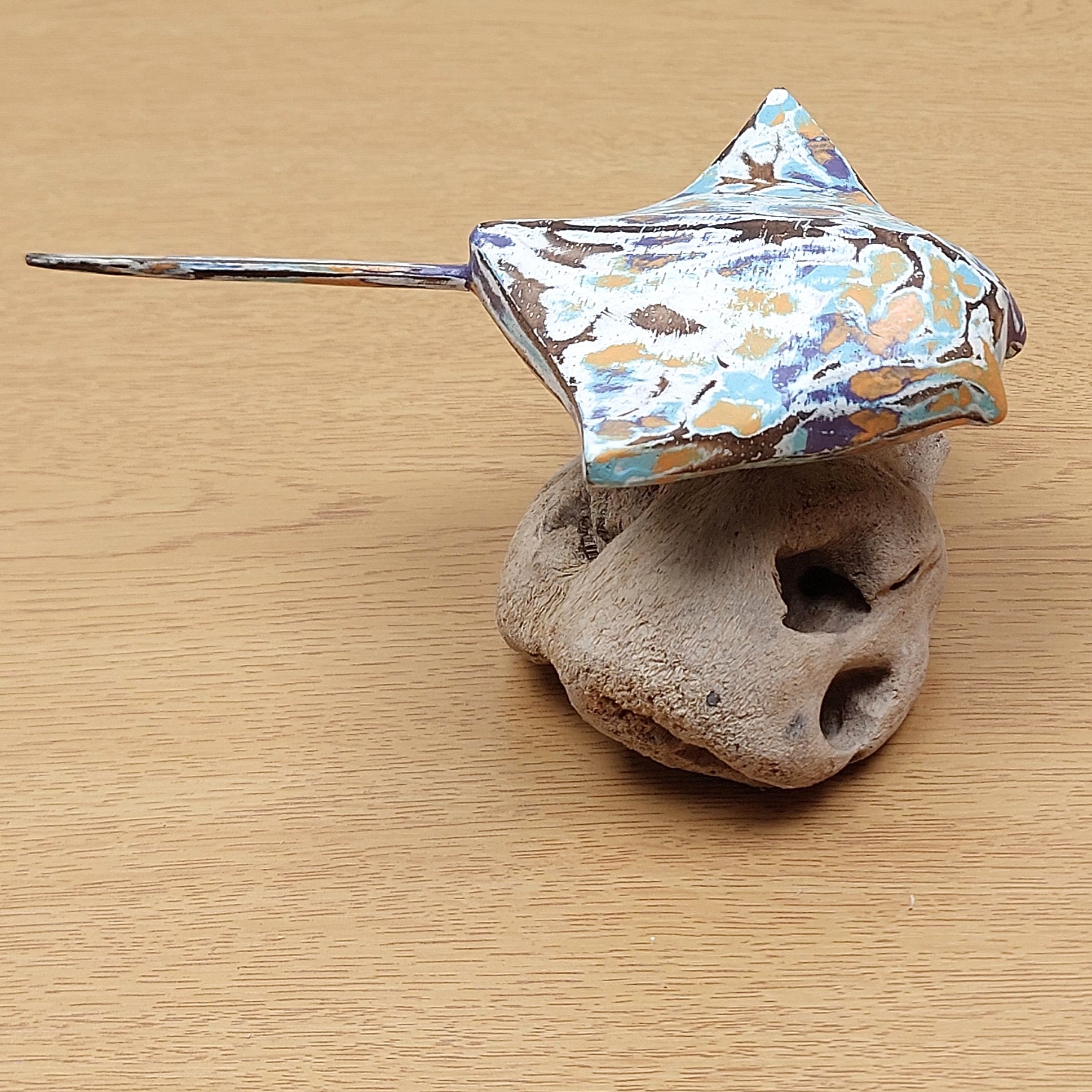 Decorative Manta Ray ornament on a piece of driftwood against a wooden background