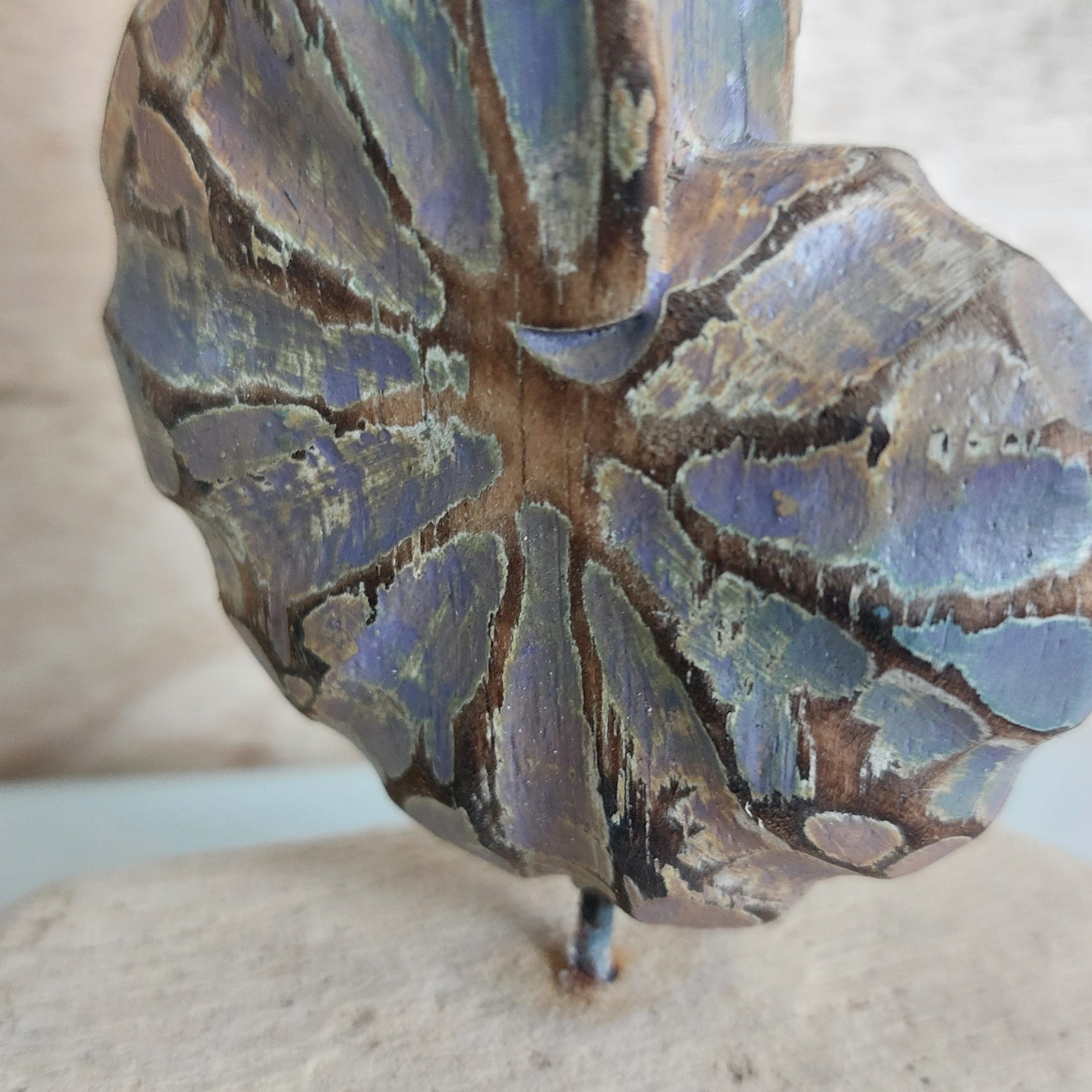 Close-up of a hand made wooden shell ornament with blue and brown colors on a neutral background