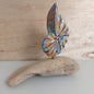 Hand carved and painted wooden shell figurine mounted on a piece of driftwood with a wooden background