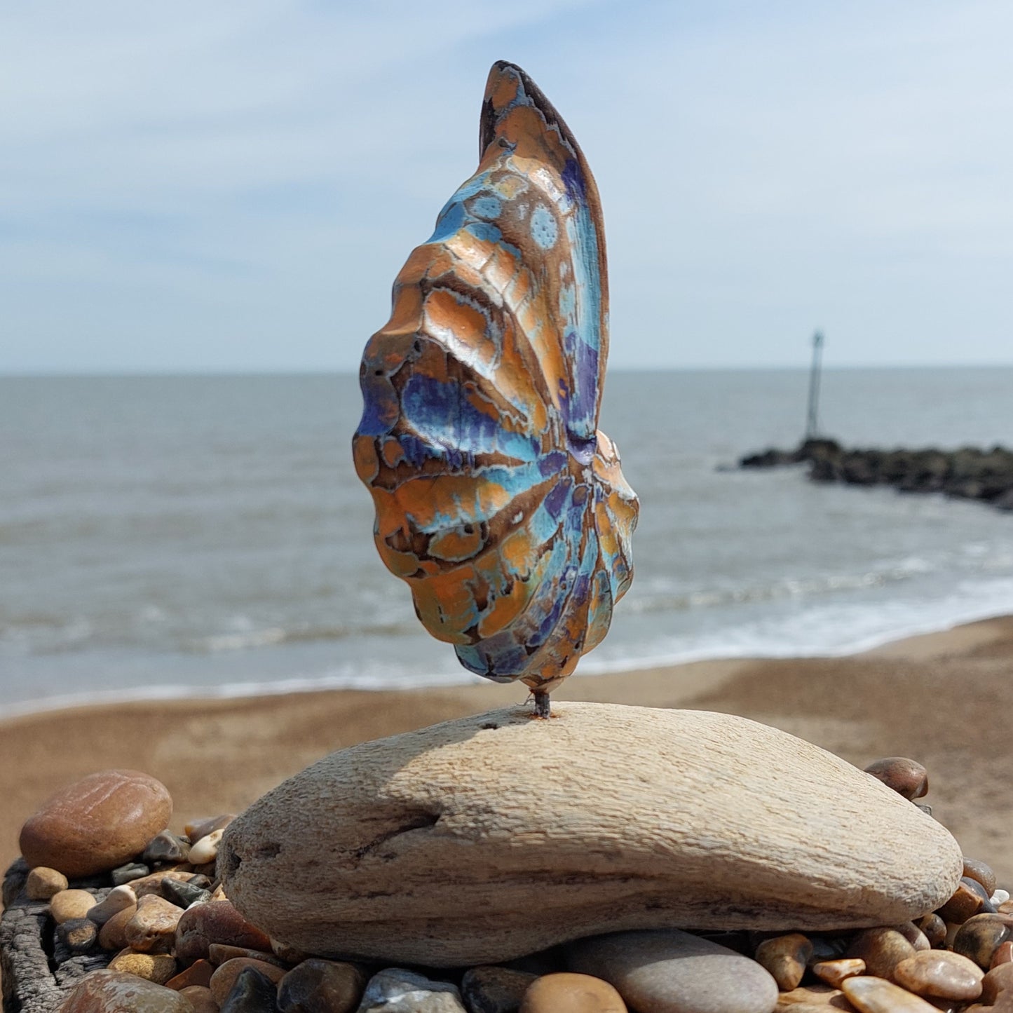 Decorative shell sculpture on a rock with ocean and sky in the background