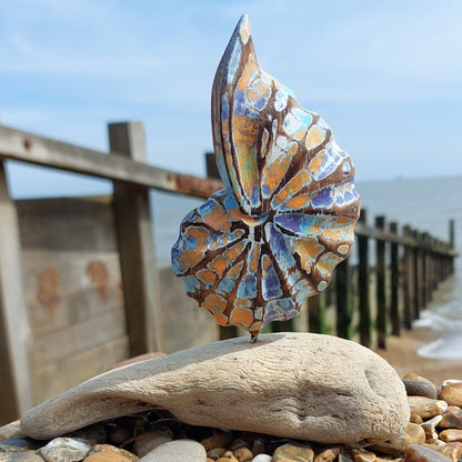 Decorative wooden shell sculpture on a rock by a wooden pier with ocean view