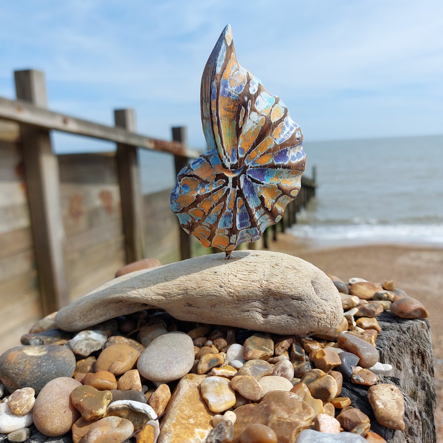 Decorative shell sculpture on a wooden surface with a blurred natural seascape background
