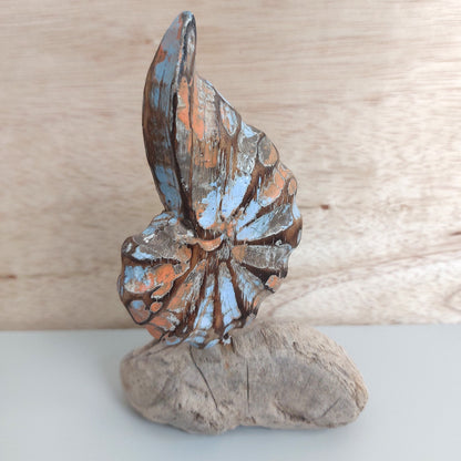 Decorative hand carved and painted wooden shell sculpture on a wooden base with a natural wood background