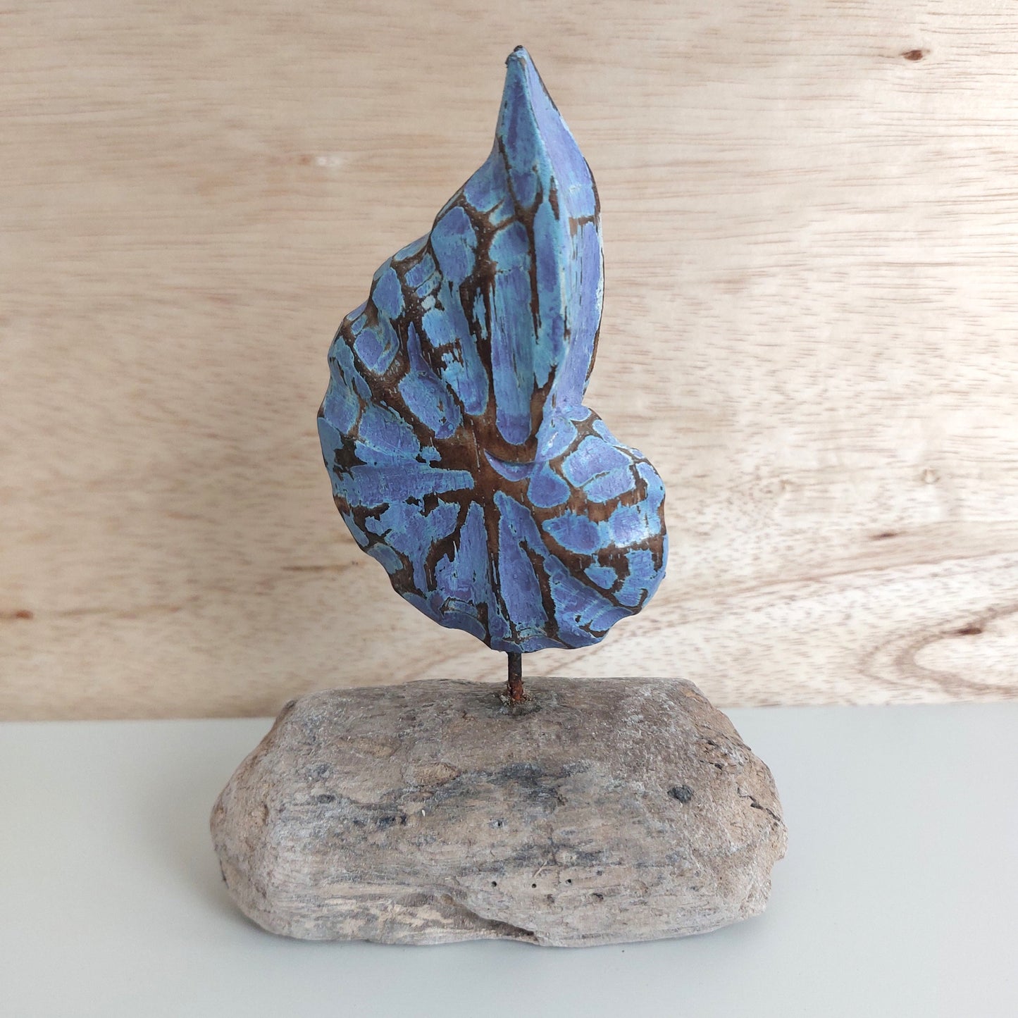 Blue wooden shell sculpture made in Bali, on a wooden base with a wooden background