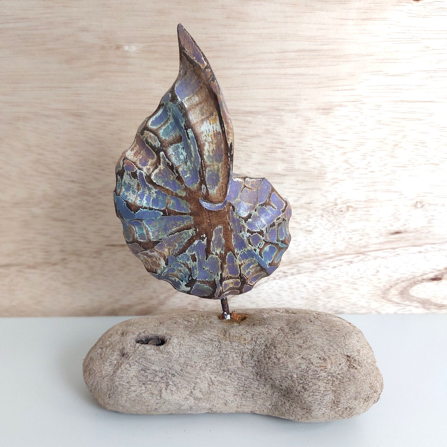 Decorative handmade and painted wooden shell sculpture on a wooden base with a wooden background