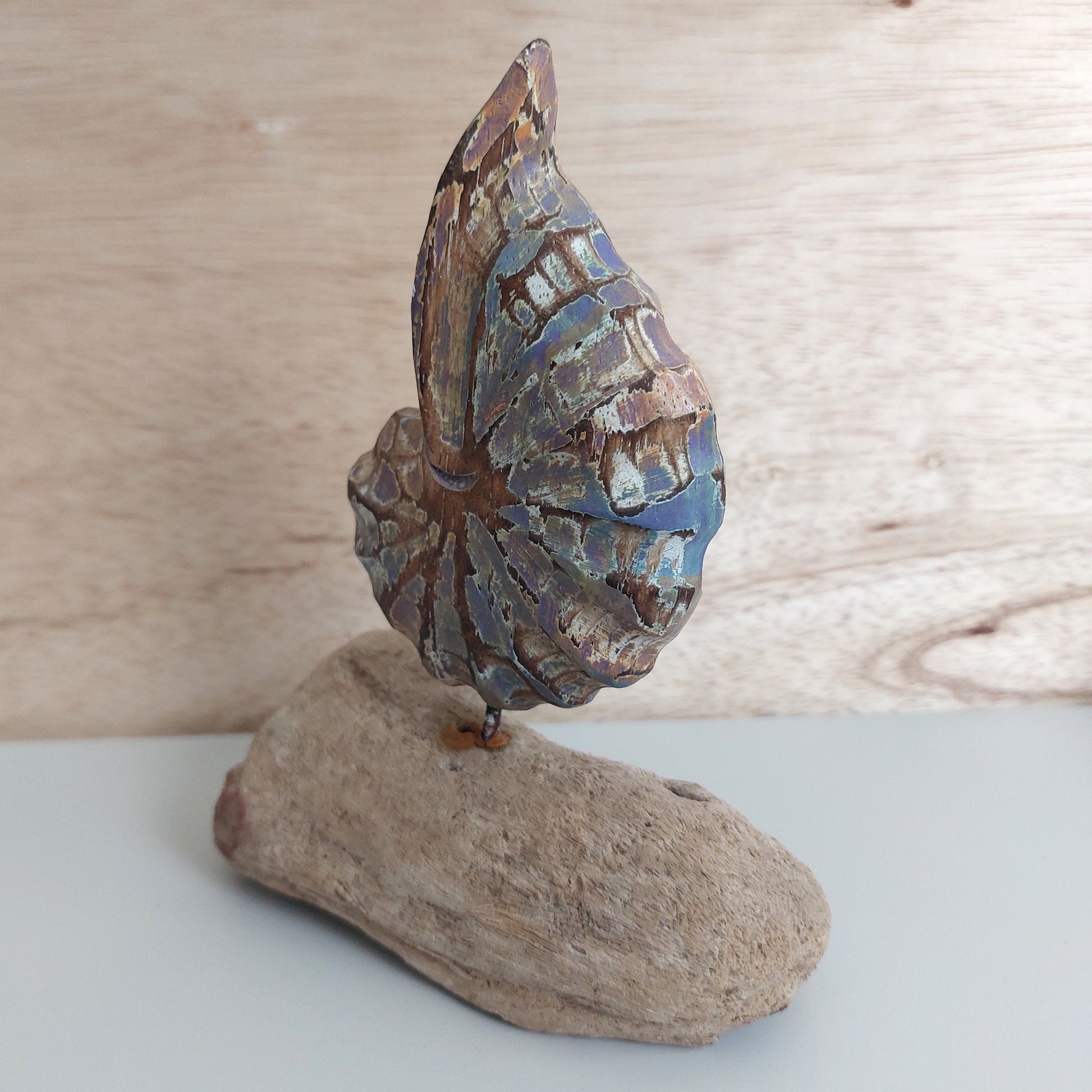 Decorative handmade and painted wooden shell on a wooden base against a wooden background