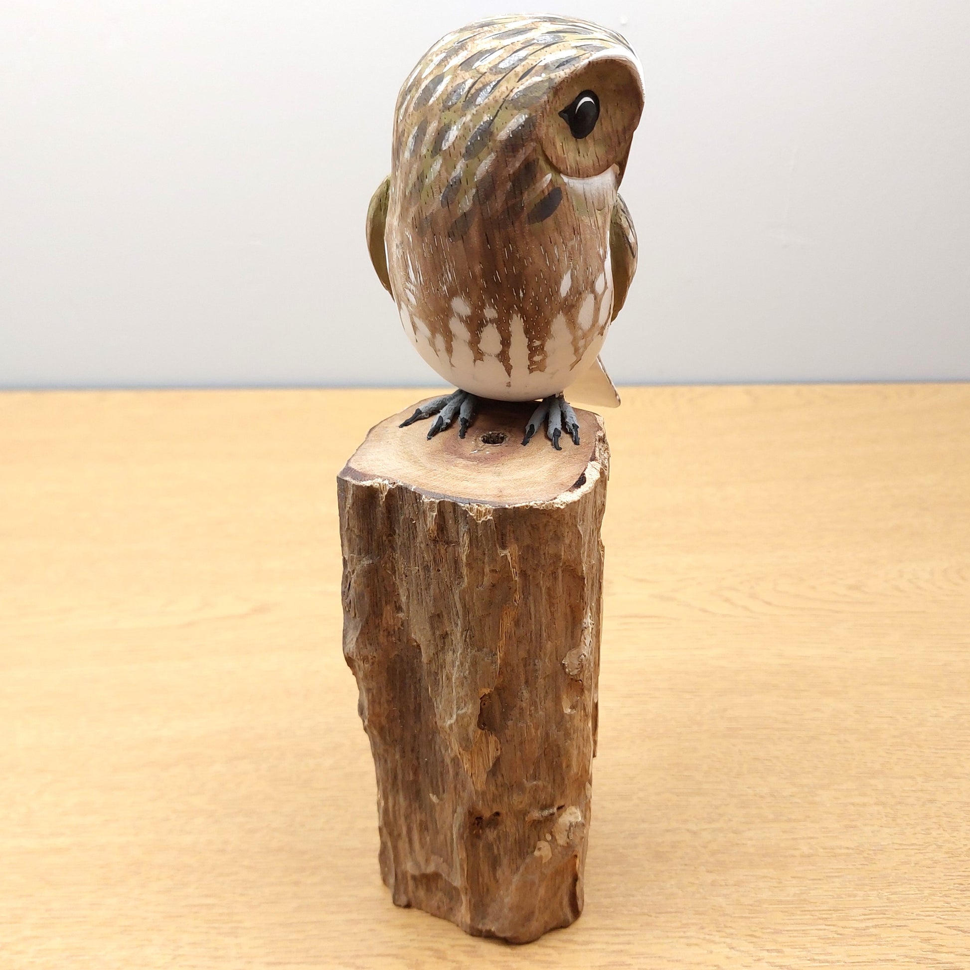 Ornate Wooden owl figurine on a wooden base against a plain background