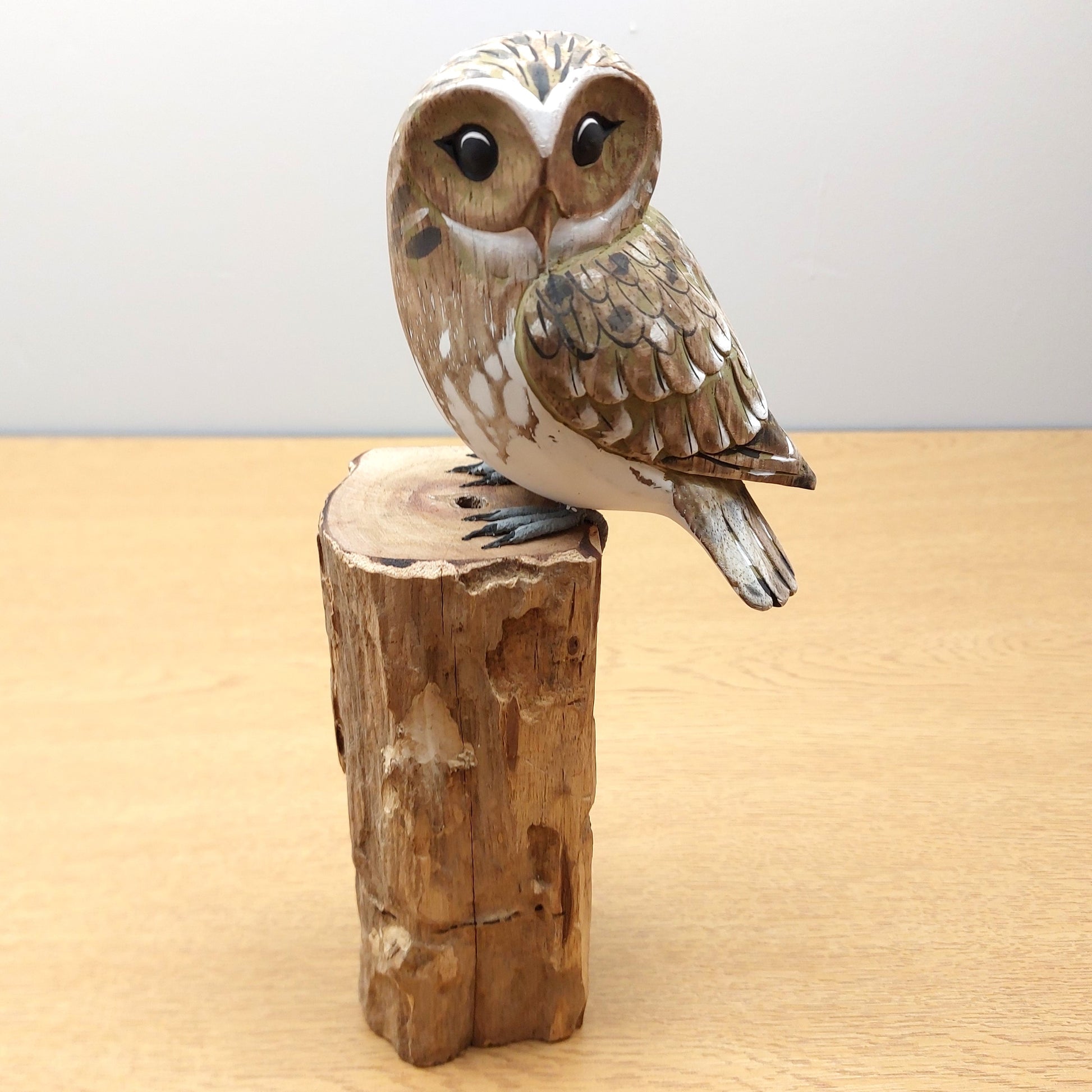 Wooden owl figurine on a wooden block against a plain background