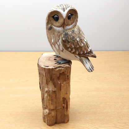 Wooden owl figurine on a wooden block against a plain background