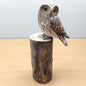 Wooden carved and painted owl figurine perched on a cylindrical wooden log base against a light background