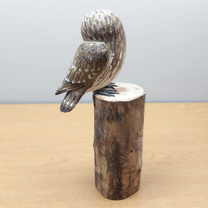 Hand carved and painted wooden owl sculpture on a wooden log from Bali against a light gray background