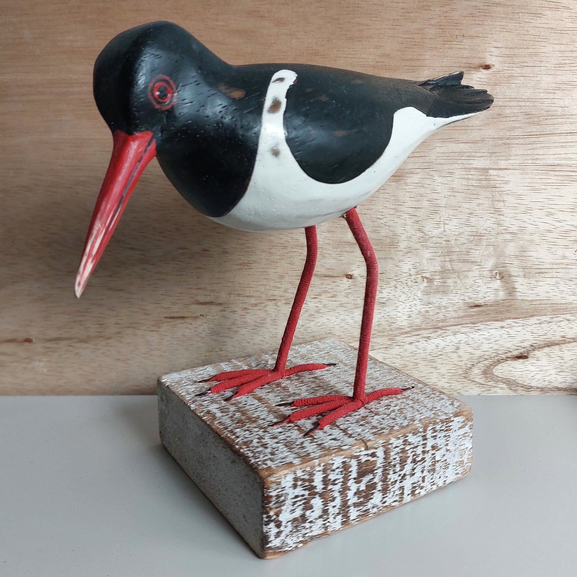 Hand Painted Wooden Oystercatcher bird figurine with a red beak on a wooden block against a wooden background