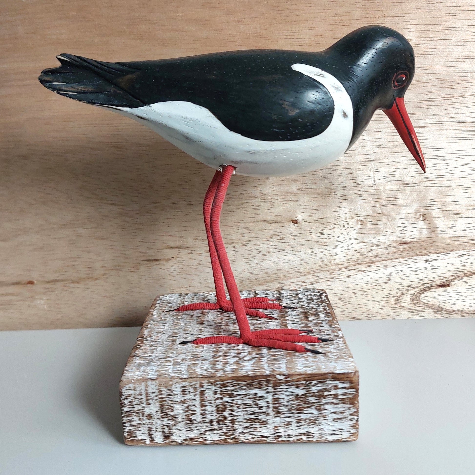 Wooden hand carved in Bali Oystercatcher bird figurine on a wooden block with a neutral background