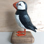 Wooden puffin figurine on a wooden base with a neutral background